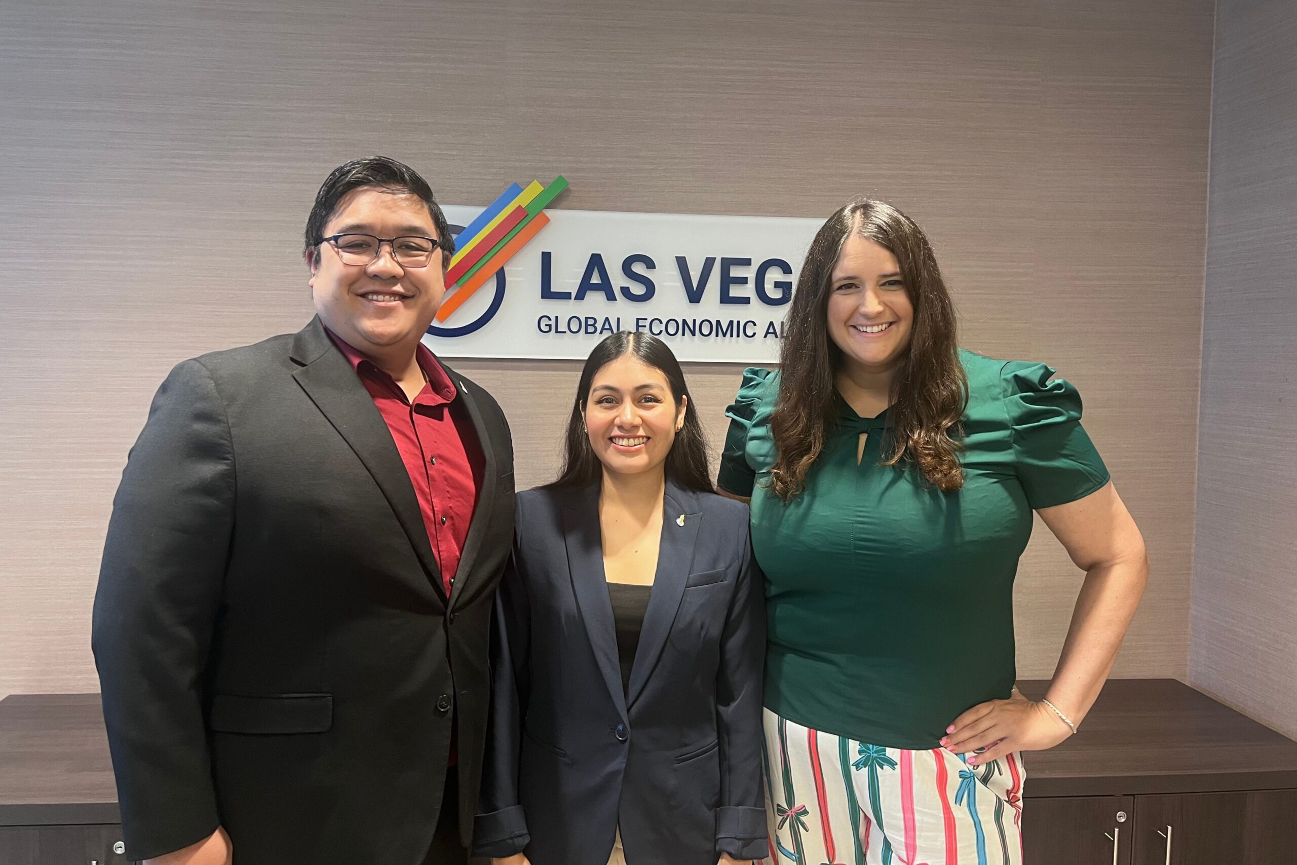 Three people standing in front of the LVGEA sign