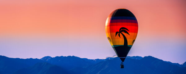 Hot air balloon on dusk skyline with mountains in the distance