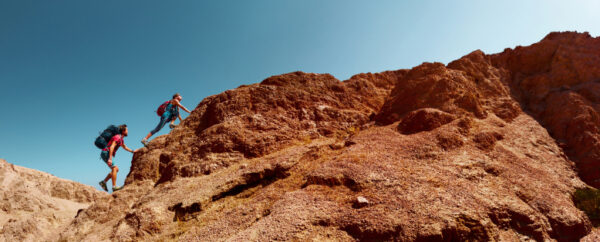 Two hikers climbing a red rocky mountain