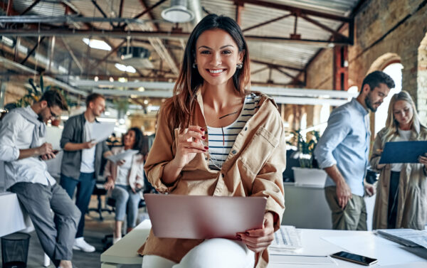 Young business people in office with a woman smiling facing the camera.