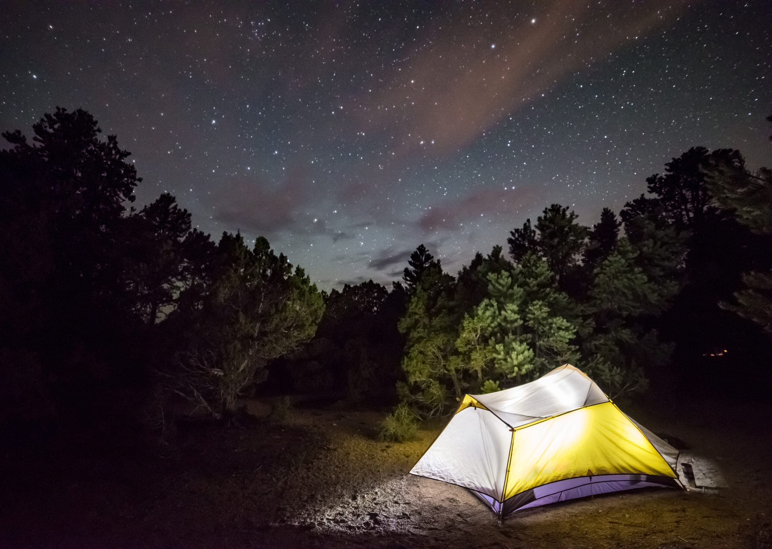 Glowing camping tent under dark skies and spectacular stars