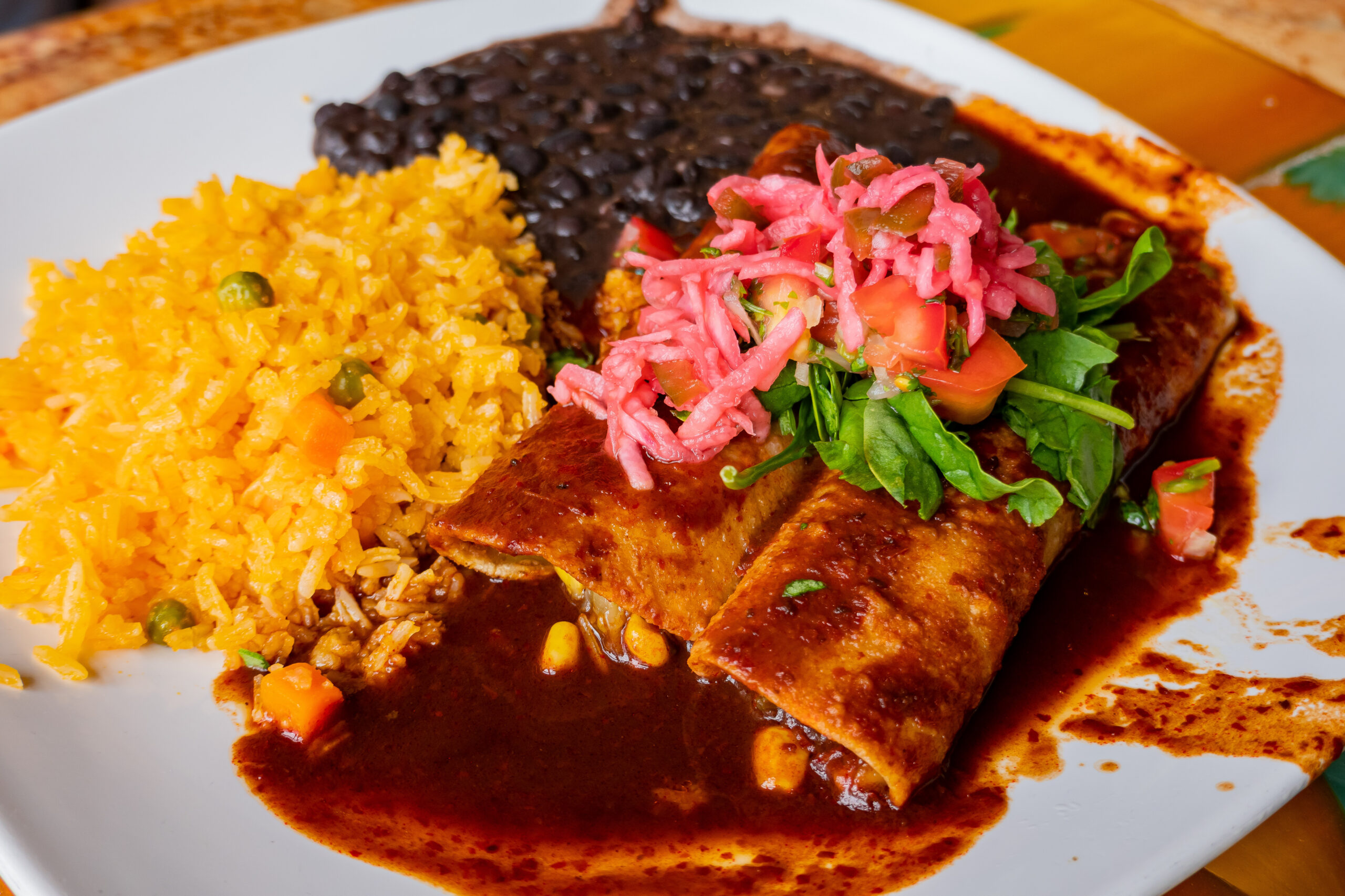 Mexican food on a white plate, beans, rice, burrito